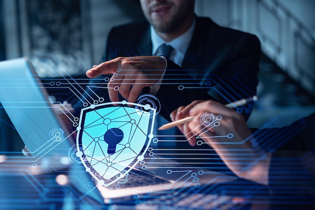 Two colleagues working together to protect clients confidential information and cyber security IT hologram padlock icons modern office background at night time