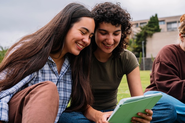 Two college students using a tablet on campus grass