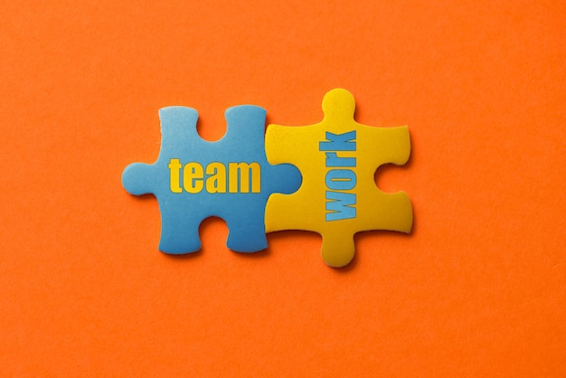 Photo two colored details of puzzle with text team work on orange, yellow and blue,