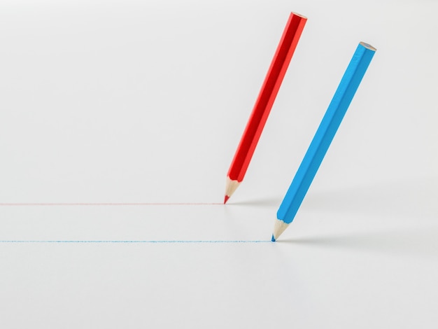 Two colored pencils drawing straight lines on a white background. The concept of cooperation.