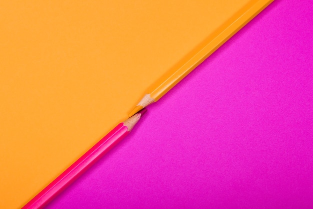 Two colored pencils isolated on two different color papers background