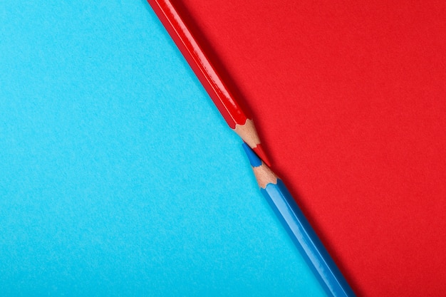 Two colored pencils isolated on two different color papers background