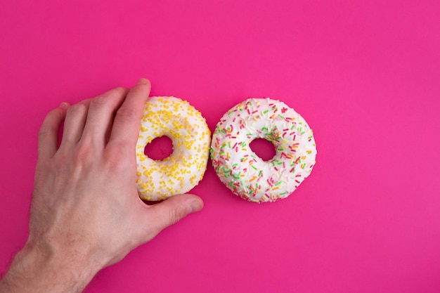 Two colorful donuts and hand