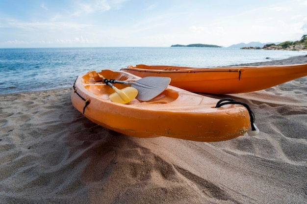 Two colorful orange kayaks on a sandy beach ready for paddlers in sunny day