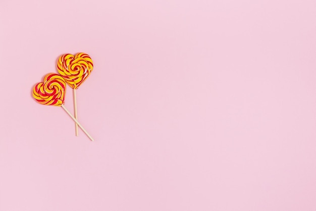 Two colorful striped lollypops on the pink background A beautiful gift for Valentines day