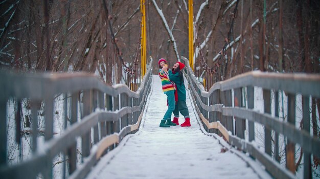 Two colorful young happy women taking photos on the winter bridge