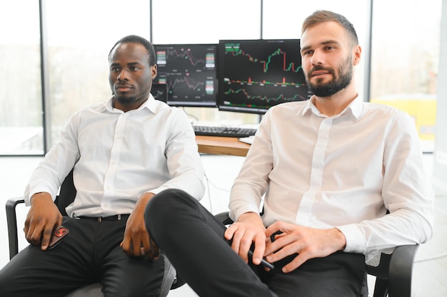 Photo two confident businessmen financial analysts or investment advisers sitting at office desk