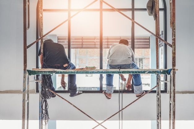 Two construction worker installing sets of metal and plastic window in hotel