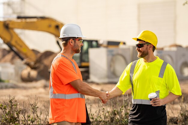 Двое строителей в шлеме на строительстве зданий работают менеджеры строительной площадки