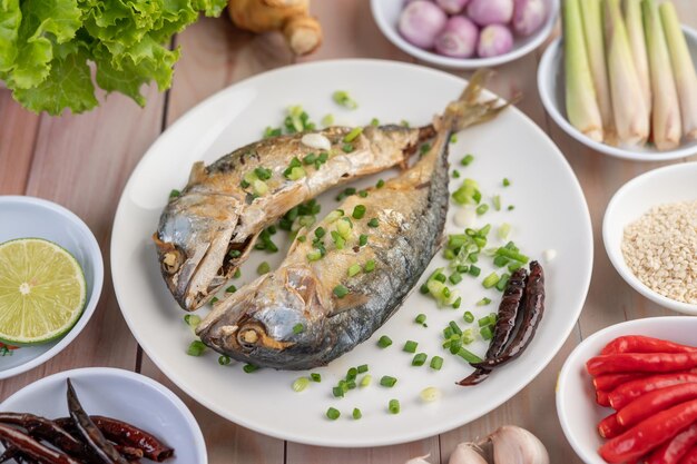 Two cooked mackerel placed in a white dish sprinkled with spring onions