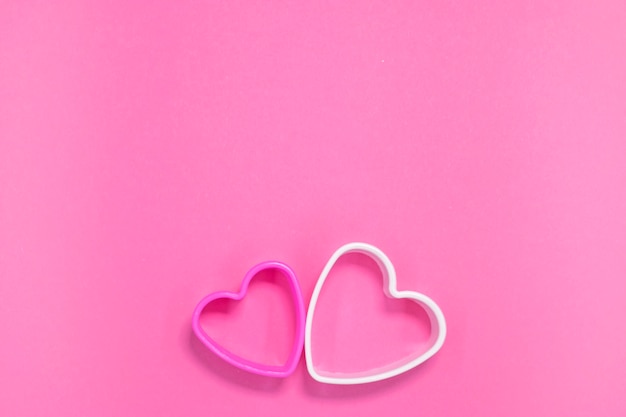 Two cookie molds in heart shape on pink