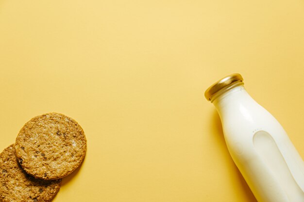 2つのクッキーと黄色の壁紙上の牛乳瓶