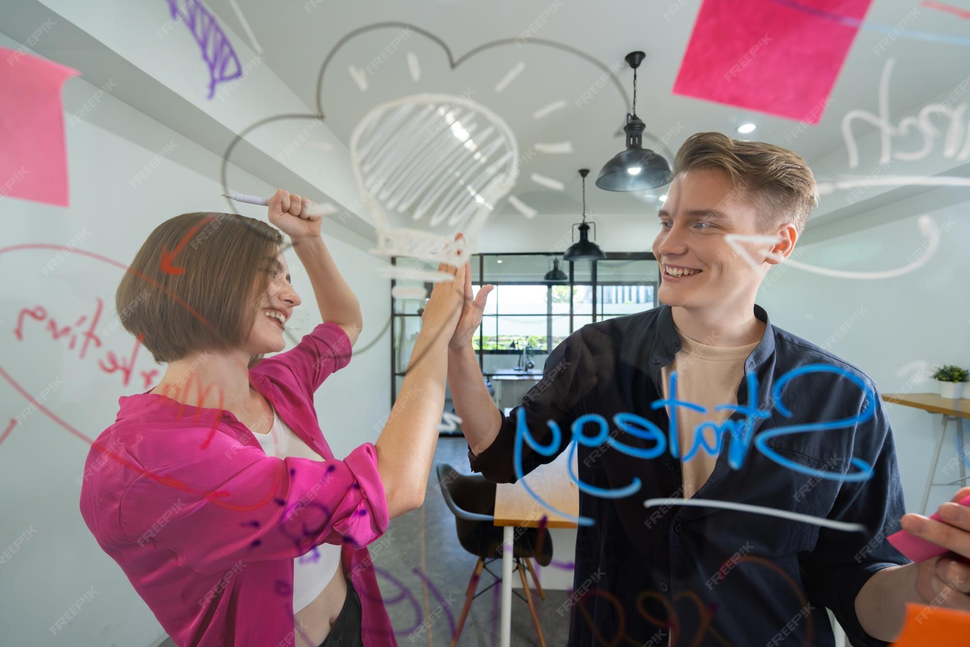 Premium Photo | Two cooperative business people giving a high five to 