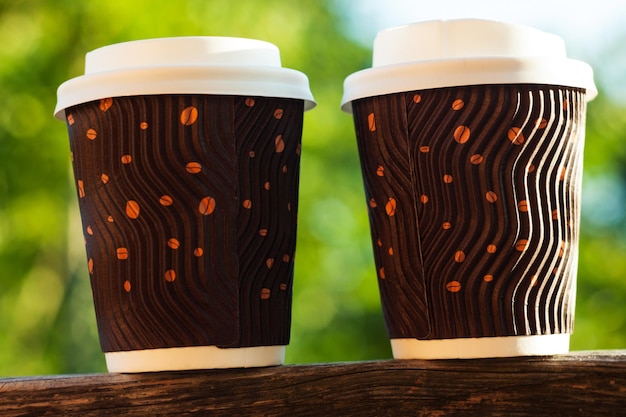 Two corrugated coffee cups on wooden balcony natural daylight blurred background Beverages shop discount Hot drinks sale banner Merchandise promo design Coffee to go Take away food lifestyle concept