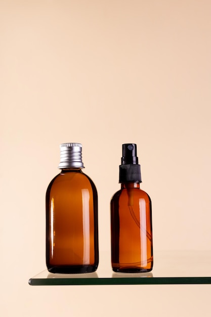 Two cosmetics dark amber glass bottles on beige background Closeup copyspace Beauty blog salon treatment concept minimalism brand packaging mock up