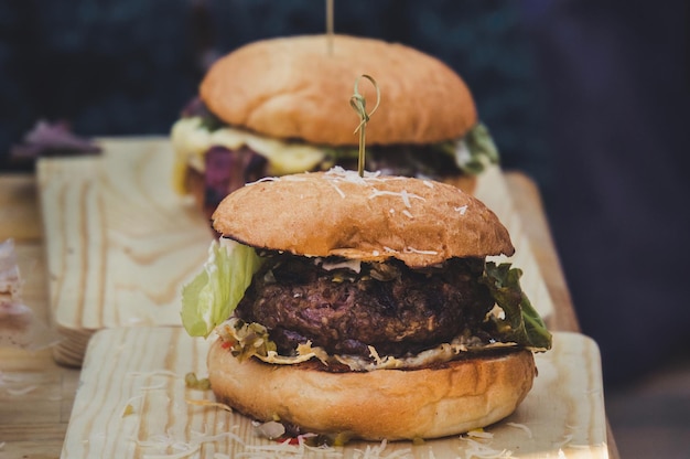 Two craft beef burgers on wooden table isolated