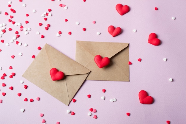 Два крафт-бумаги почтовый конверт с сердечками многоцветный сладкий леденец. Любовь сообщение или подарок концепции.