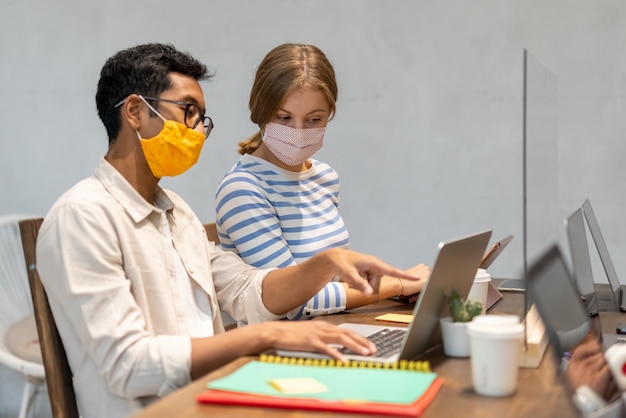 Photo two creative freelancers work in protection with face masks on a project collaborative activities in a coworking space concept of resume activities diversity and cooperation despite the pandemic