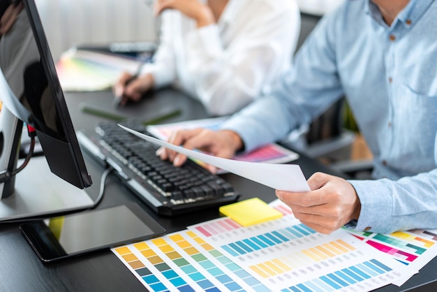 Foto due team di designer grafici creativi che lavorano sulla selezione del colore e disegnano sulla tavoletta grafica grafico di campioni di campioni di colore per la colorazione della selezione ispirandosi alla creatività sul posto di lavoro