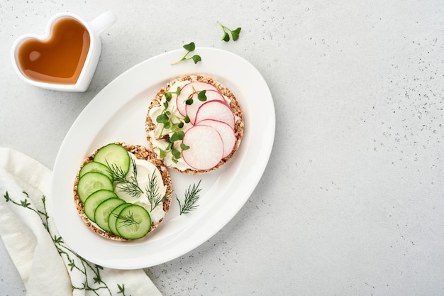 two crispy buckwheat bread cake gluten free with cream cheese, red radish, cucumber and microgreen