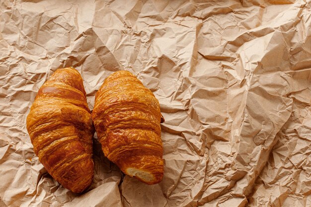 Two croissants on a background of crumpled craft brown paper