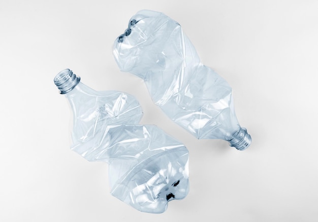 Two crumpled plastic water bottles on grey background