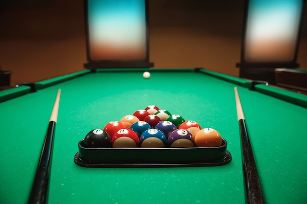 Two cues and pyramid on a billiard table.