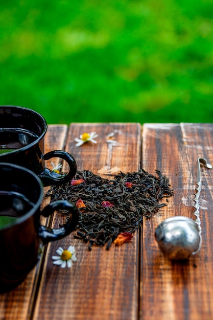 Two cup of tea near dry leaves of black tea make in heart shape