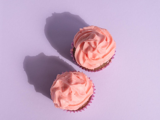 Two cupcakes on a purple background with space for text top view