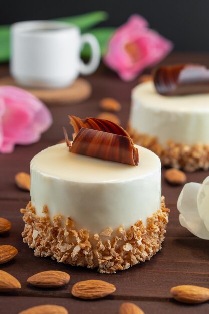 Two cupcakes with chocolate white coffee cup almond and tulips on wooden table Selective focus