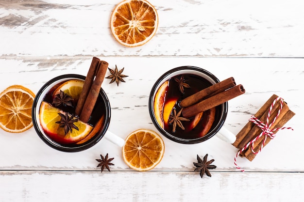 Two cups of autumn mulled wine or gluhwein with spices and orange slices on rustic table top view. Traditional drink on autumn and winter holiday.