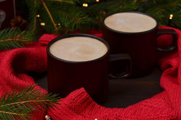 테이블 근접 촬영 빨간 스웨터와 크리스마스 트리에 카푸치노 두 컵