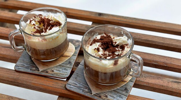 Two cups of capuccino placed on an old wooden sled in the  snow