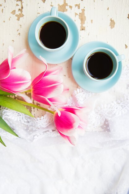 Due tazze di caffè e tulipani rosa su una vecchia tavola