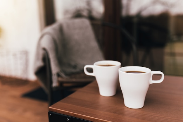 夕方の日没時に木製の茶色のテラスのテーブルにコーヒー2杯。リラクゼーション、静かな田舎の生活のコンセプト。素敵なカップルの夜