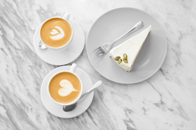 Two cups of coffee with cake art on white background
