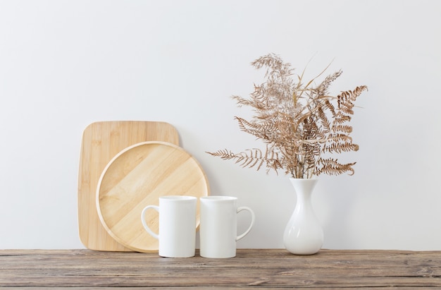 Two cups and dried flowers on white kitchen