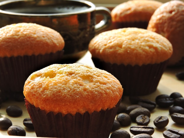 Two cups of espresso, mini muffins, coffee beans.