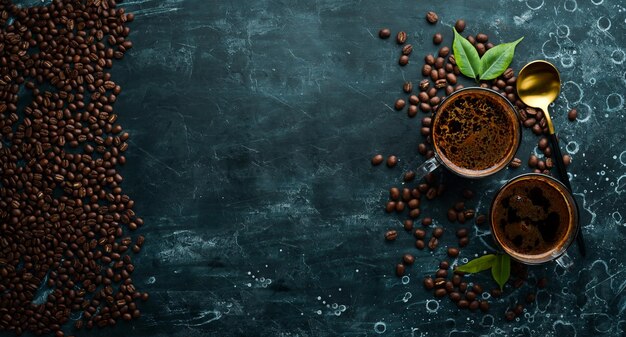 Two cups of fragrant coffee and coffee beans on a black stone background Top view Free space for text