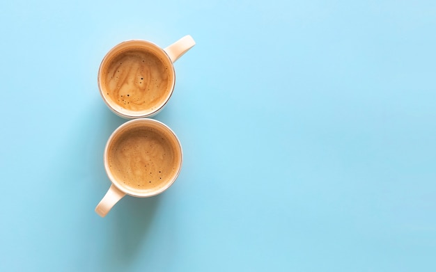 Two cups of freshly brewed coffee with a beautiful creamy foam on a gently blue background. Flat lay.Close up. Copy space.