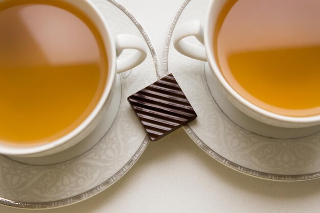 Two cups of green tea with a small piece of chocolate