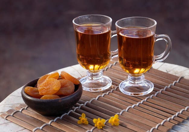 Photo two cups of hot tea with dried apricots on wooden table in the garden