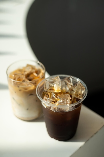 Photo two cups of iced coffee with ice on a table in a cafe.