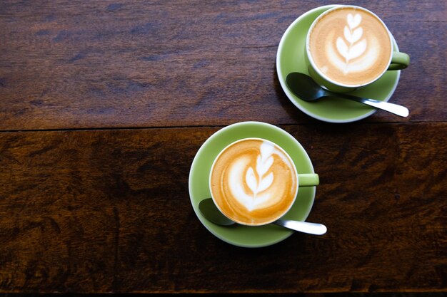 Two cups of tasty cappuccino with latte art on wooden table background