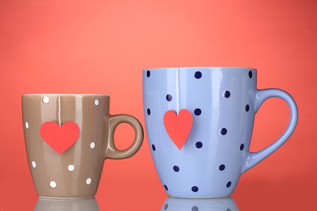 Two cups and tea bags with red heart-shaped label on red background