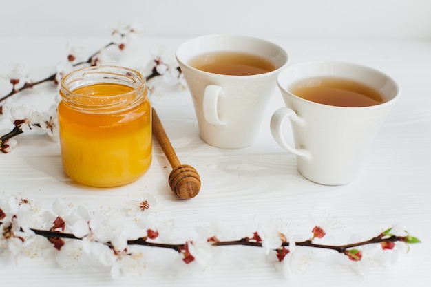 two cups of tea and honey on wooden background