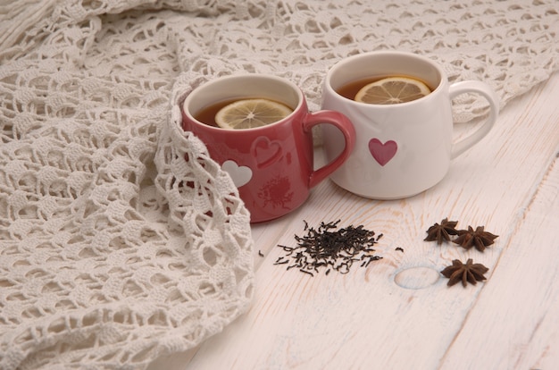 Two cups of tea with lemon and scarf on wooden boards