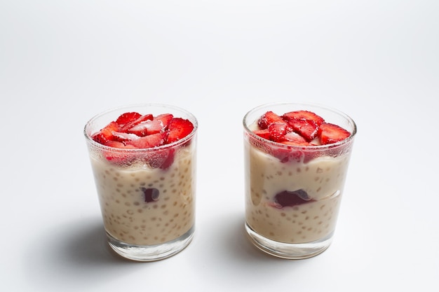 Two cups of vegan dessert pudding with strawberries on white Super food