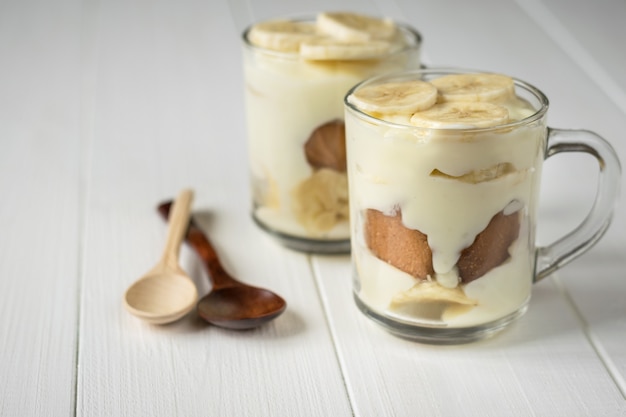 Two cups with banana pudding and two colorful spoons on the table.