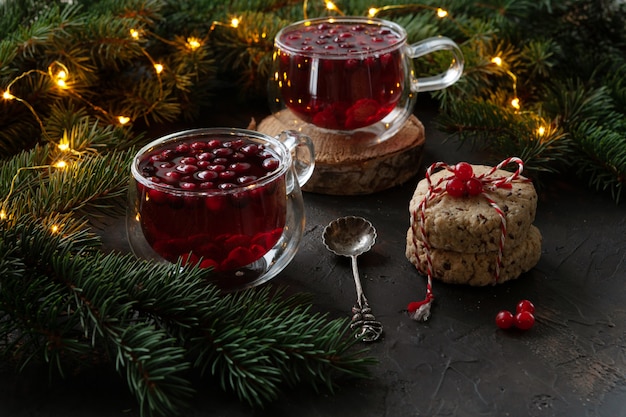 Two cups with hot Christmas spicy drink with cranberry and cakes. 